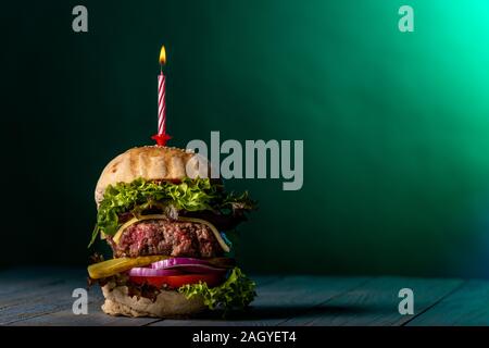 single cheeseburger with a burning candle Stock Photo