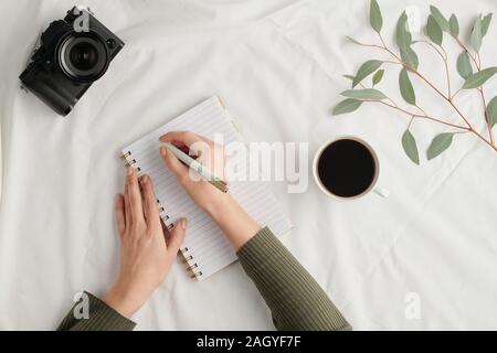 Hands of young woman with pen over open notebook making working notes Stock Photo