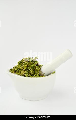 Stack of wild Thyme flowers and leaves in white porcelain mortar isolated on white background Stock Photo