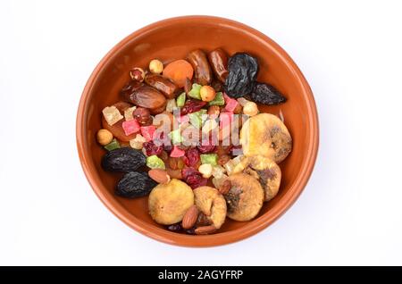 Different sorts of dried fruits in orange clay bowl isolated on white background, view from above Stock Photo