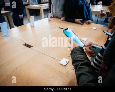 Paris, France - Nov 3, 2017: Overhead view of customers admiring inside Apple Store the latest professional iPhone smartphone manufactured by Apple Computers comparing with older model phone Stock Photo