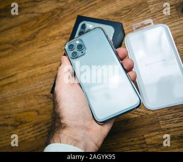 Paris, France - Oct 4, 2019: Man hand holding latest Apple Computers triple-lens iPhone 11 Pro with green color transparent Clear Case case after unboxing Stock Photo