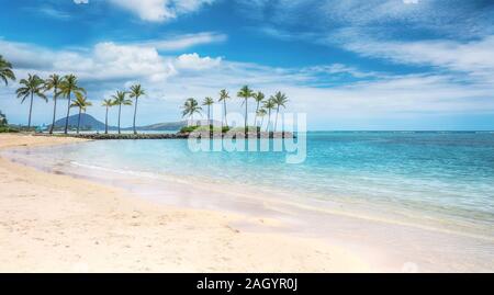 A beautiful beach scene in the Kahala area of Honolulu, with fine white sand, shallow turquoise water, a view of coconut palm trees and Diamond Head. Stock Photo