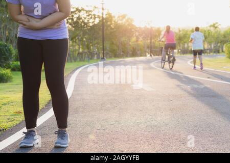 Young woman touching her painful abdominal, suffering from abdominal pain while exercising and running, Sport and exercise concept. Stock Photo