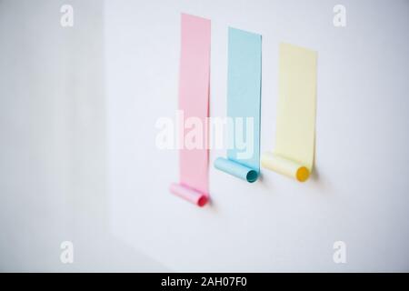 Colorful chart made up of blank pink and smaller blue and yellow sticky papers stuck on whiteboard or wall Stock Photo