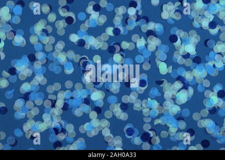 Festive multicolored confetti scattered on blue background. Holiday concept. Pastel polka dots texture. Stock Photo