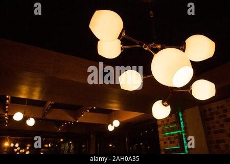 A luminous chandelier shines on the ceiling in the room. Stock Photo