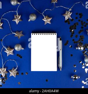 Christmas, winter composition. Notebook with isolated white page, open diary, sketch book mock-up scene on blue surface. Stock Photo