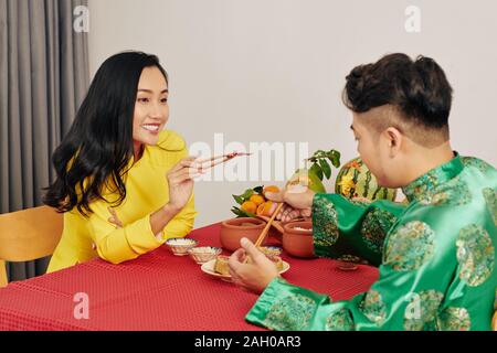 Romantic young couple having tasty food when celebrating Lunar New Year at home Stock Photo