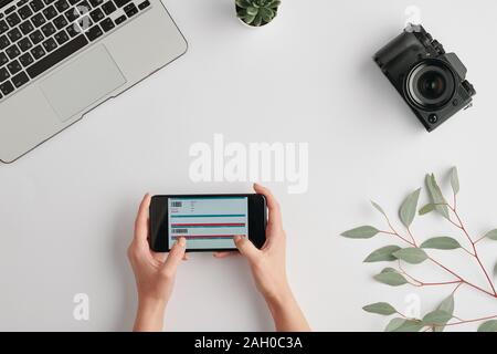 Overview of hands of young woman holding smartphone with ticket form on screen Stock Photo
