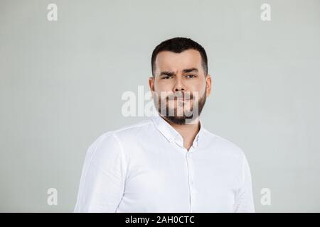 Portrait of young frowned handsome bearded man on gray background. facial expression Stock Photo