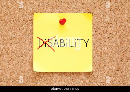 Turning the word Disability into Ability with red marker on yellow sticky note pinned with red push pin on cork bulletin board. Stock Photo