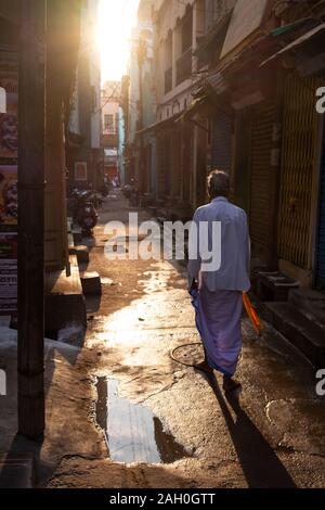 Rear view of senior man walking in alley at sunrise in Trichy, Tamil Nadu, India Stock Photo
