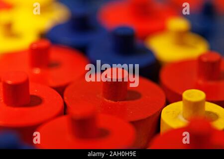 red, yellow and blue wooden play pieces in close up Stock Photo