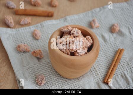Candied almonds in wooden bowl with cinnamon on a wooden table Stock Photo