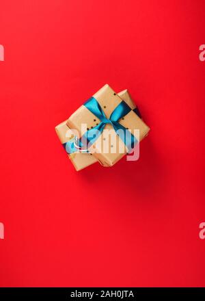 Christmas new year gift boxes wrapped in craft paper with green ribbon and candy canes on red bold color backdrop. Festive flat lay background Stock Photo