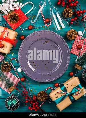 Christmas dark green background with gray empty dish and festive ornament around, gift boxes. Holiday new year dinner lunch concept Stock Photo