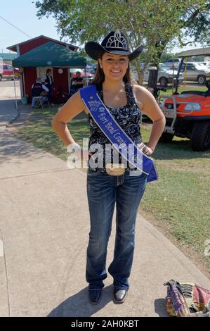 The beautiful brunette Fair Queen of the Fort Bend County State fair posing on a pathway with her sash near to the entrance of the event. Stock Photo