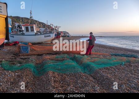 Hastings, East Sussex, UK. 23rd December 2019. Hastings fisherman sorts his nets at sunrise on a sunny, mild December day. Carolyn Clarke/Alamy Live News. Stock Photo