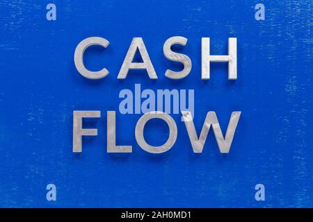 The words cash flow laid on blue painted board with thick silver metal aphabet characters. Stock Photo