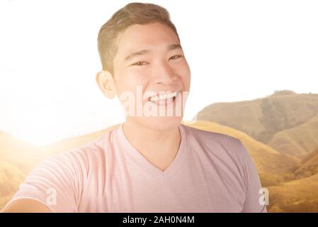 Asian man making selfie using the camera phone with sunlight background Stock Photo