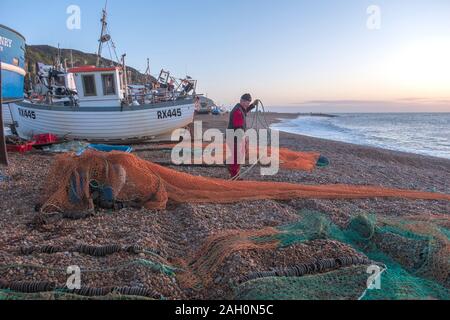 Hastings, East Sussex, UK. 23rd December 2019. Hastings fisherman sorts his nets at sunrise on a sunny, mild December day. Carolyn Clarke/Alamy Live News Stock Photo