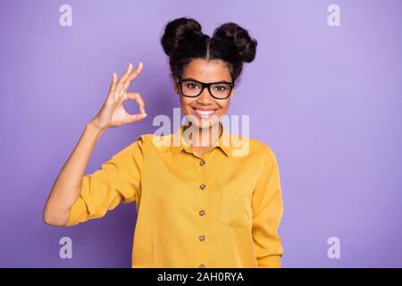 Photo of amazing pretty dark skin lady showing okey symbol best reliable worker diligent student wear specs yellow shirt isolated purple color Stock Photo