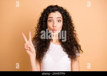 Hi there. Closeup photo of amazing lady showing v-sign symbol sending air kisses handsome guy wear white casual outfit isolated beige pastel color Stock Photo