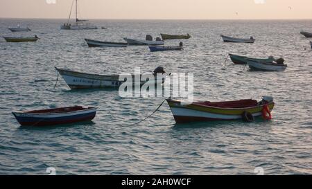 View of many colorful small fishing boats and skiffs at anchor in a calm ocean in the Cape Verde Islands on Sal Island Stock Photo