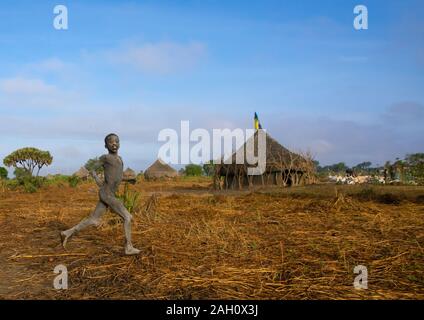 Boy running in front of a traditional Mundari tribe village, Central Equatoria, Terekeka, South Sudan Stock Photo