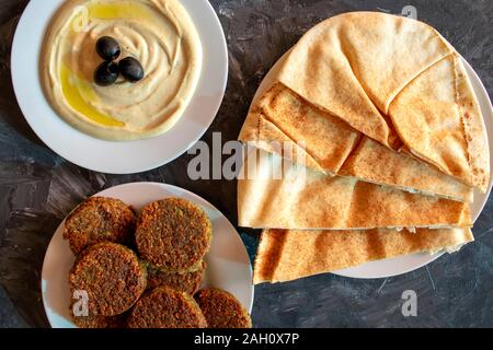 Famous traditional Arabic, Middle East, Israel cuisine. Tahini sauce, pita bread and falafel on gray background. Flat lay, top view. Stock Photo