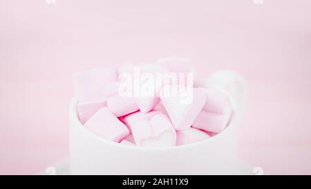 Cup of pink marshmallow hearts on a pale pink background. Valentines day love concept. Copy space, 16:9 panoramic format Stock Photo