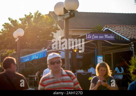 people walking in the sunset on a busy boulevard in front of little restaurant