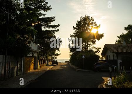 sunset on a road leading to sea in the distance Stock Photo