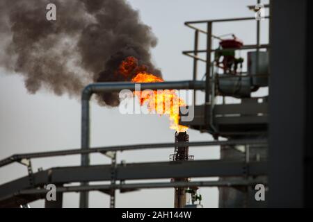 Burning gas torch with black smoke. Gas processing and oil refinery plant. Stock Photo