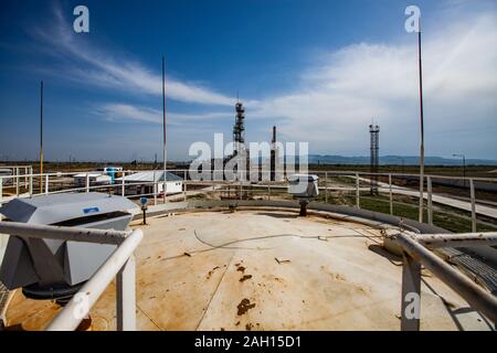 Grey distillation column on bright sun at a blue sky with clouds on oil refinery plant in a desert.. Stock Photo
