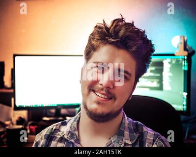 Portrait of smiling man with computer and colored light on background. Shiny day. Copy space for text. Stock Photo