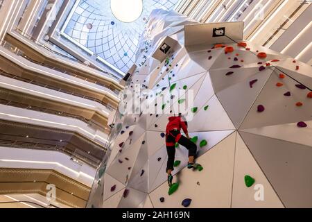 A young woman tries out the 55-meter-tall world's tallest indoor roket climbing wall at the New World City Plaza in Shanghai, China on December 20th, Stock Photo