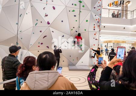 A young woman tries out the 55-meter-tall world's tallest indoor roket climbing wall at the New World City Plaza in Shanghai, China on December 20th, Stock Photo