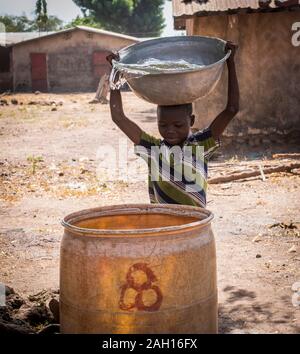 Benin, Kandi, drinking water, carrying water, african boy carrying water, african boy, pouring water, african village Stock Photo