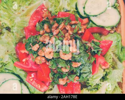 Salad with shrimps and tomatoes and greens, lettuce leaves and cucumbers, dressing from olive oil soy sauce and lemon juice and garlic Stock Photo