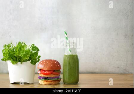 Brioche burger, vegetable smoothie and salad in a french fries container Stock Photo