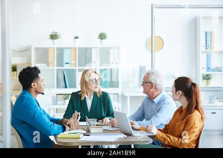 Multiethnic group of business people sitting at the table and planning work together in team during business meeting Stock Photo
