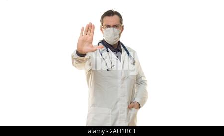 Male doctor in a orotective mask showing a STOP gesture with a palm of hand. Photo on white background. Stock Photo