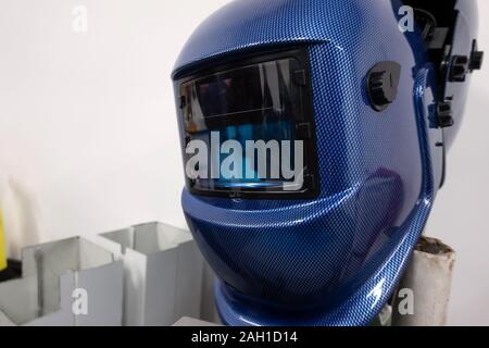 Welding helmet handing in workshop on white background. Welder protective helmet inside Stock Photo