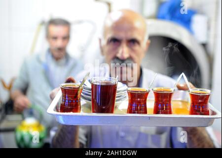 Kuwait City, Kuwait. 23rd Dec, 2019. A man prepares tea for customers at Dalalwa Cafe, in Kuwait City, Kuwait, Dec. 23, 2019. Located in the old Al-Mubarakiya market in Kuwait City, Dalalwa Cafe has a more than 100-year history. As a historical site, Dalalwa Cafe does not offer coffee, but serves black tea, lemon tea, cinnamon tea, cold drinks and shisha tobacco. It is one of the most famous tea houses in Kuwait City, where local Kuwaiti people enjoy their free time. Credit: Ghazy Qaffaf/Xinhua/Alamy Live News Stock Photo