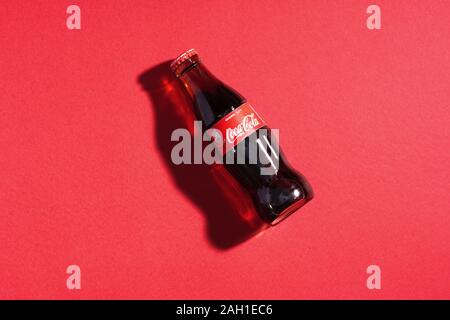 Coca Cola in glass bottle on red paper background. Italy, Milan - 15 November 2019 Stock Photo