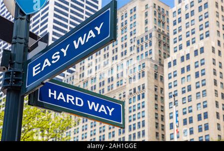 Easy way, hard way crossroads street sign, blue color road sign, Hard, easy choice concept. Highrise buildings background, Stock Photo