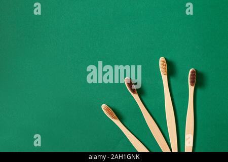 Concept of zero waste and caring for environment. Top view or flat lay concept with eco bamboo tree toothbrushes on green background Stock Photo