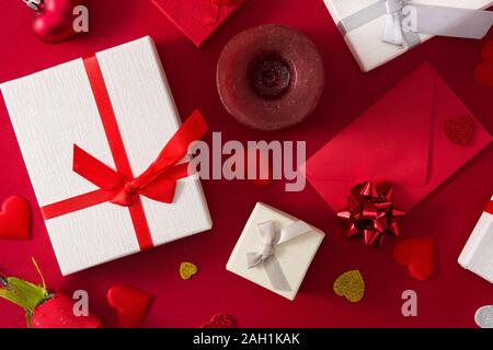 Gift boxes, red paper envelope and red hearts on red background. Top view Stock Photo